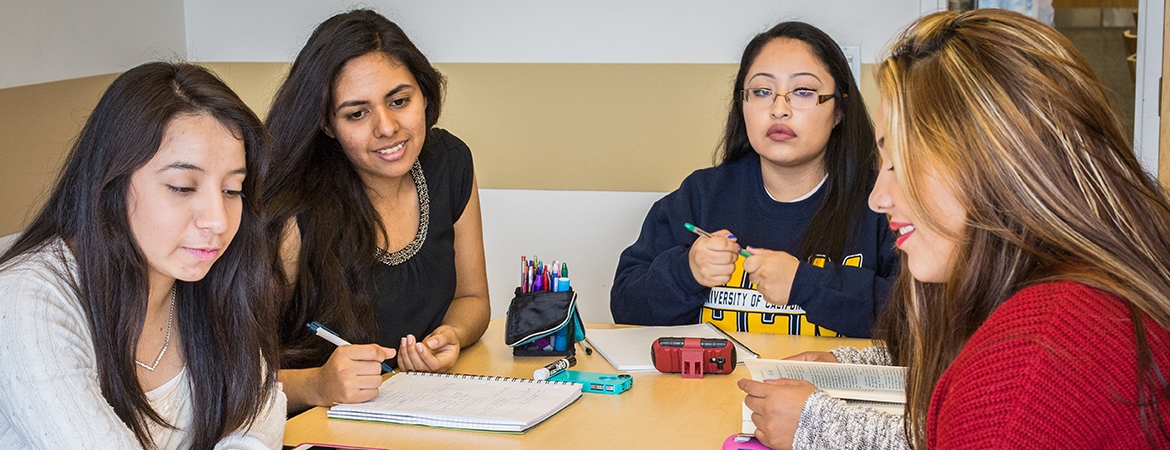 Four students sitting at a table together and reviewing notes